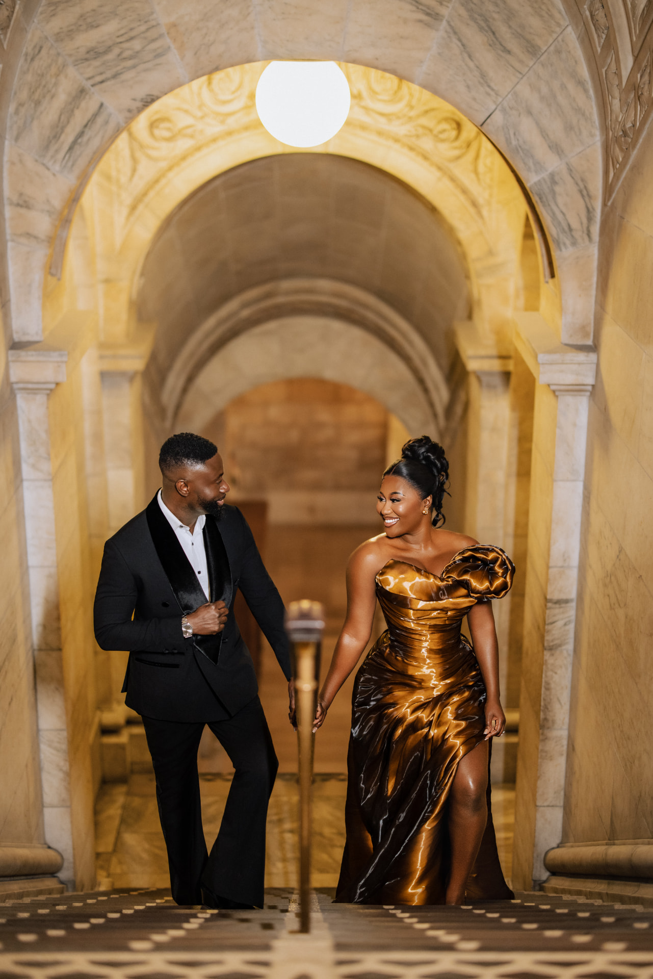 Emmanuel and Priscilla smiling together beneath the archway