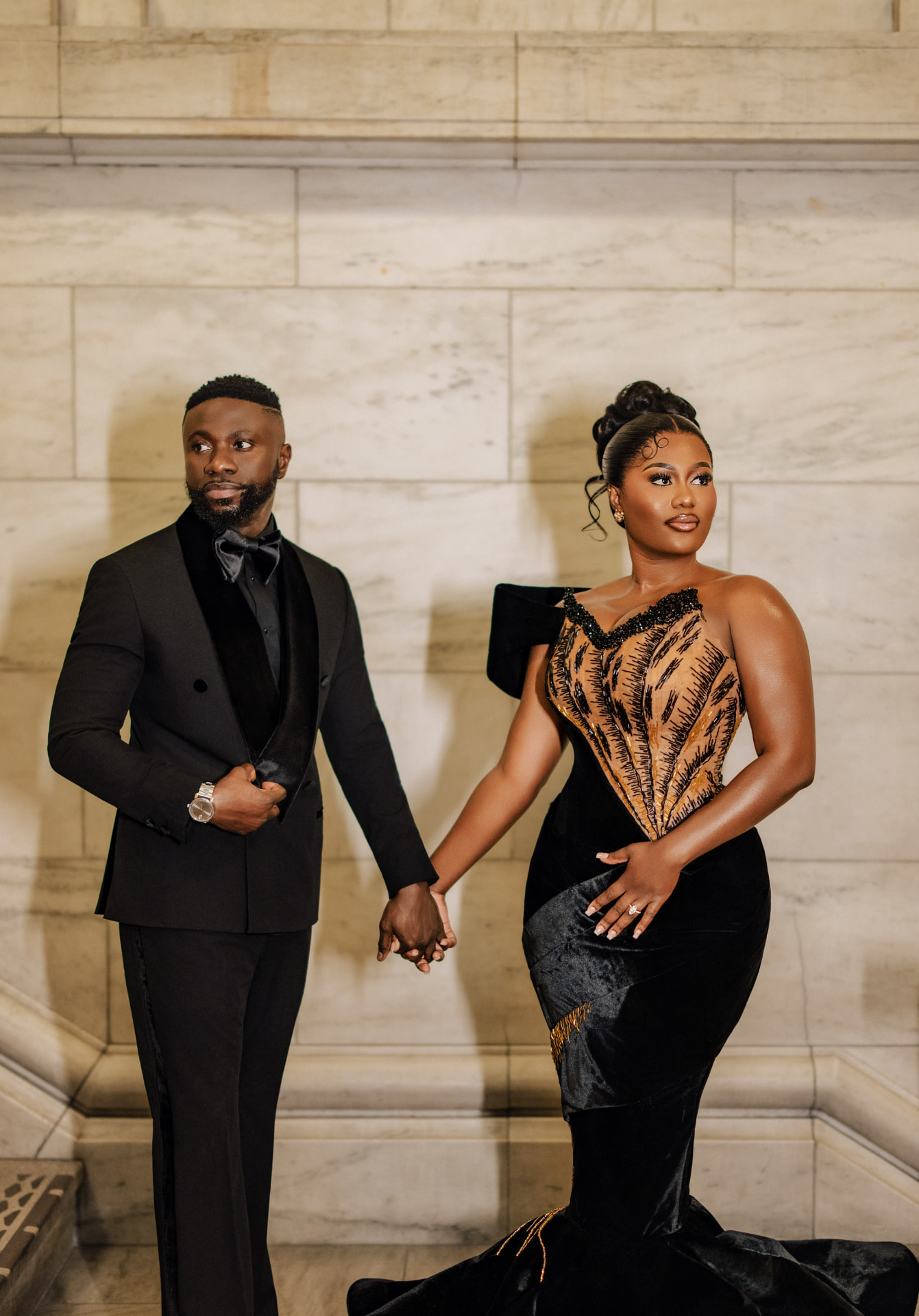 Emmanuel and Priscilla holding hands in black formal attire